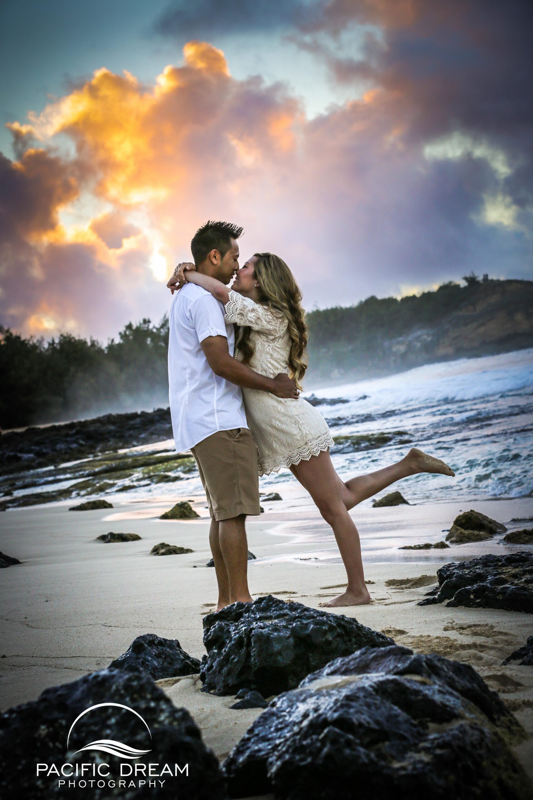 A couple sitting on the beach during sunset, holding hands and enjoying the view.